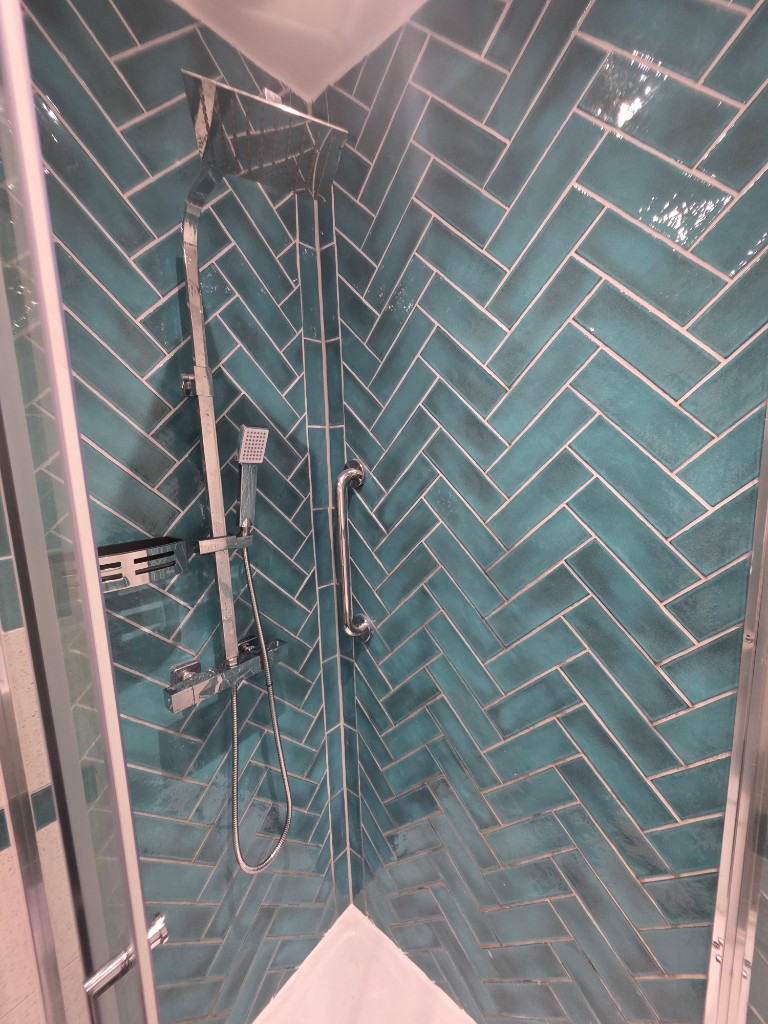 Teal herringbone shower tiling with chrome rainfall shower