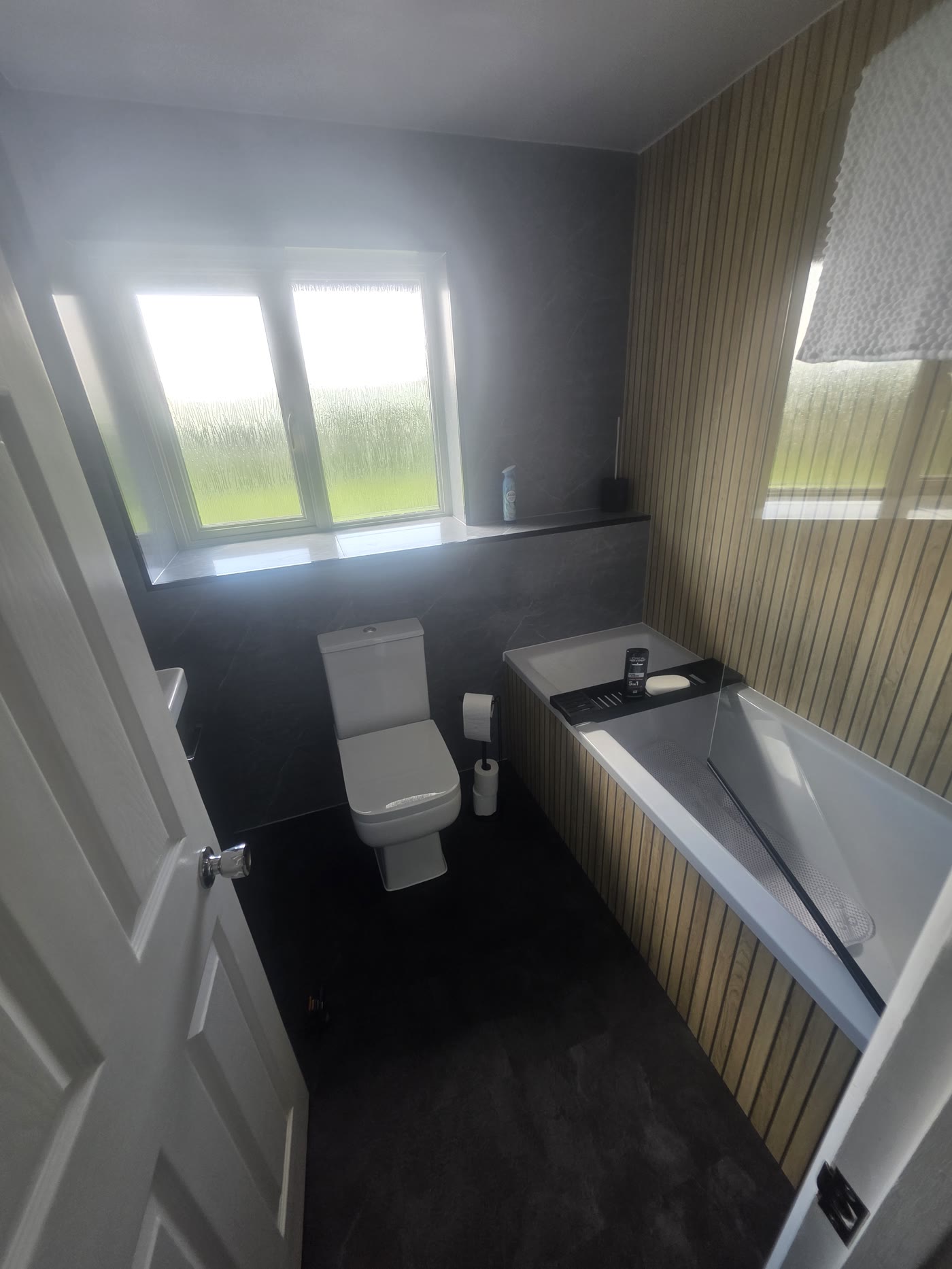 Doorway view of toilet, bath and window in Ighten Hill bathroom