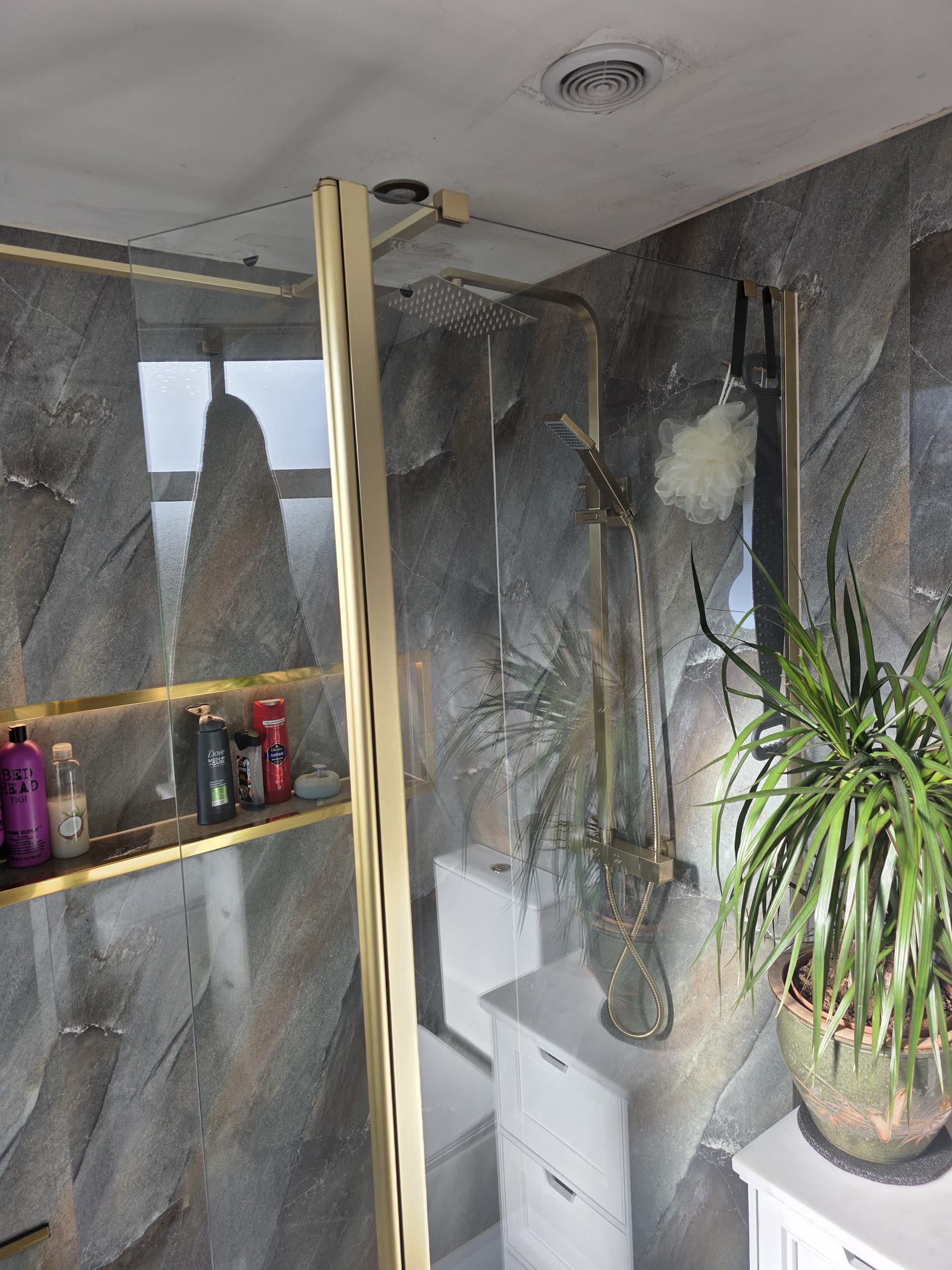 Shower enclosure detail with PVC splash panels and gold hardware