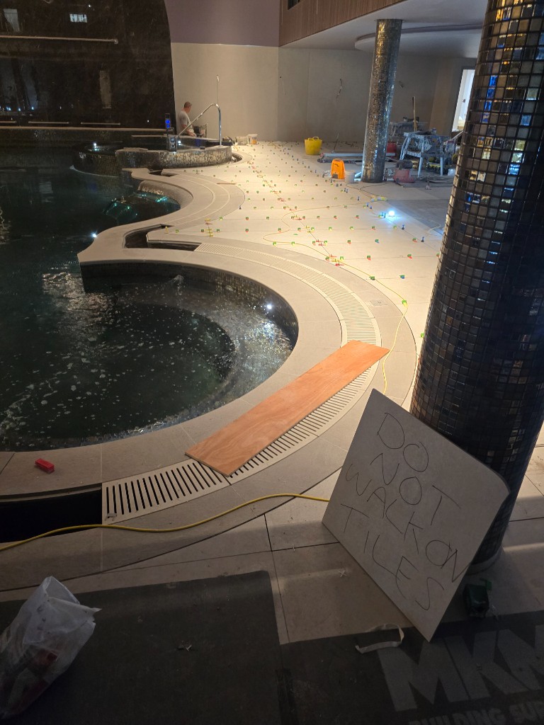 Poolside walkthrough with mosaic pillars and floor tiling underway
