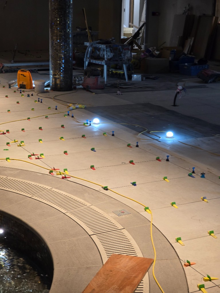 Precision leveling around curved pool drainage and mosaic edges