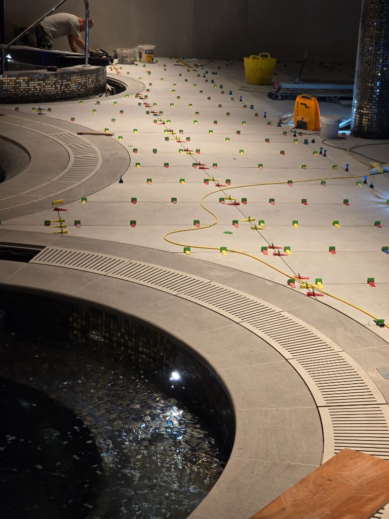 Curved pool deck tiling with laser levels and metal trim